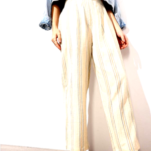 A woman modeling a beige striped two-piece outfit featuring high-waisted trousers and a matching crop top, styled with brown sandals against a white backdrop.