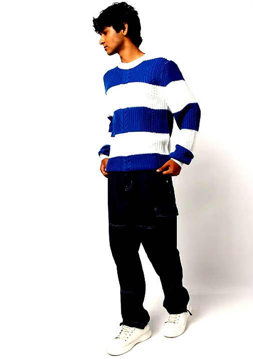  Side view of a man wearing a blue and white striped knitted sweater paired with denim.