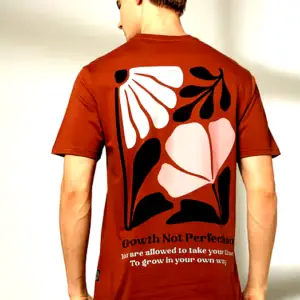 Back view of a male model wearing a DNMX T-shirt showcasing an oversized floral print and the phrase "Growth Not Perfection."