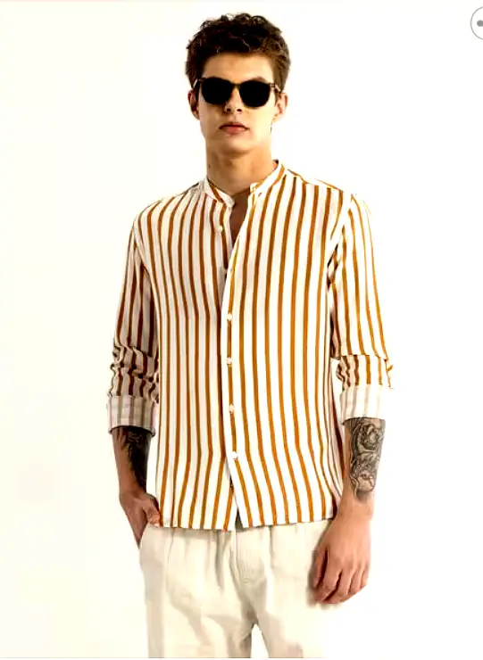 SNITCH 5 A male model wearing a mustard and white vertically striped full-sleeve shirt with a mandarin collar, paired with light-colored trousers and sunglasses.
