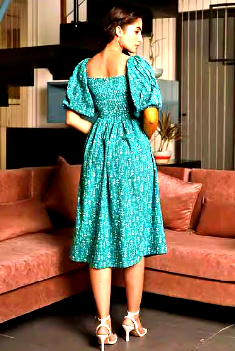 STAR WORD 4 Back view of a woman wearing a teal smocked midi dress with puffed sleeves.