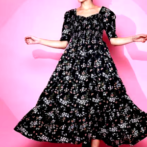 Woman twirling in a black floral smocked maxi dress with puffed sleeves and a tiered hem.