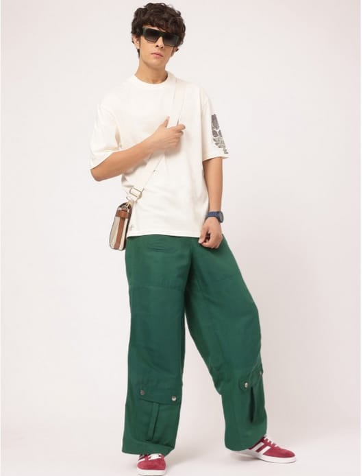 Man posing in green cargo pants and white oversized t-shirt with sunglasses.