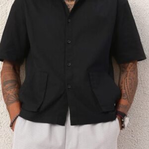 Person wearing a black short-sleeve button-up shirt with a collar and two front pockets.