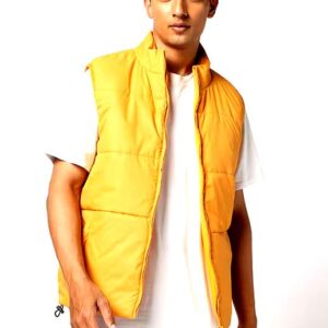 Model wearing a vibrant yellow puffer vest styled over a white t-shirt and beige shorts, showcasing a casual yet trendy look.