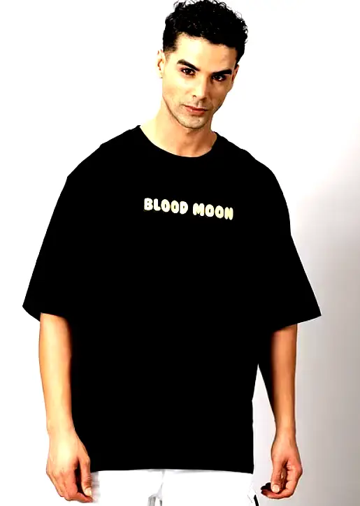THE HOLLANDER 4 Close-up view of a man in a black oversized T-shirt featuring "Blood Moon" text print on the chest.
