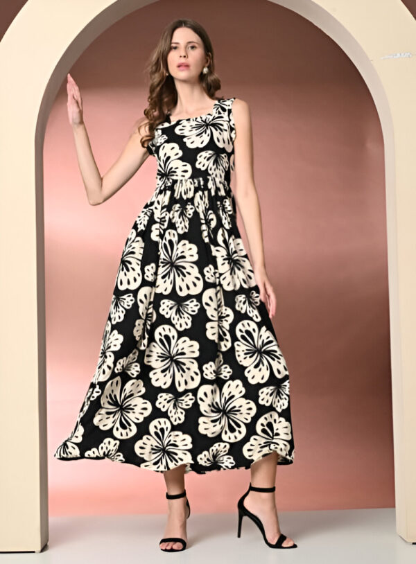 Woman wearing a sleeveless black maxi dress with large white floral patterns, cinched waist, and paired with black high heels, posing under an arch with a peach-toned background.