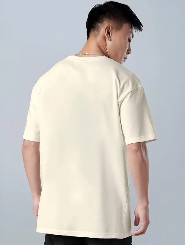 Man wearing a plain cream-colored T-shirt, photographed from the back against a light grey background.