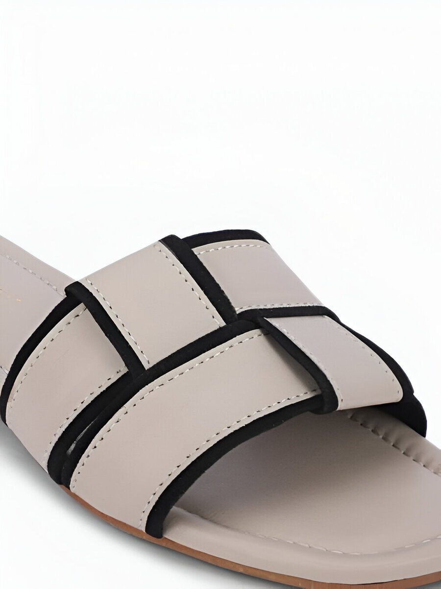 Dressberry (Women) 3 Close-up of Dressberry footwear beige slip-on sandal with black piping details and crisscross straps, showcasing its stylish design.